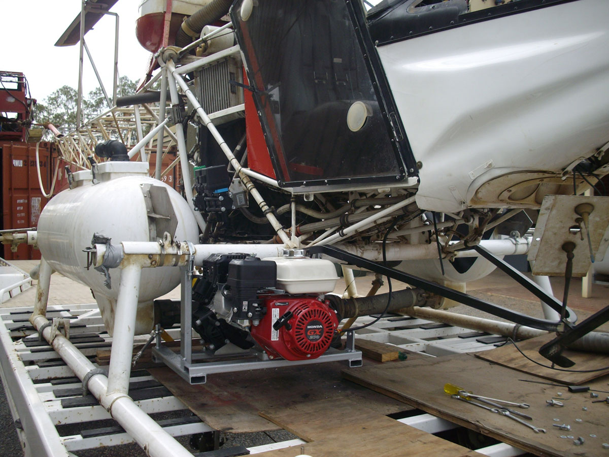 The fuel tank for the spraying equipment is mounted on a custom made platform hung from a support suspended between the helicopters undercarriage and the strut for the landing ski.